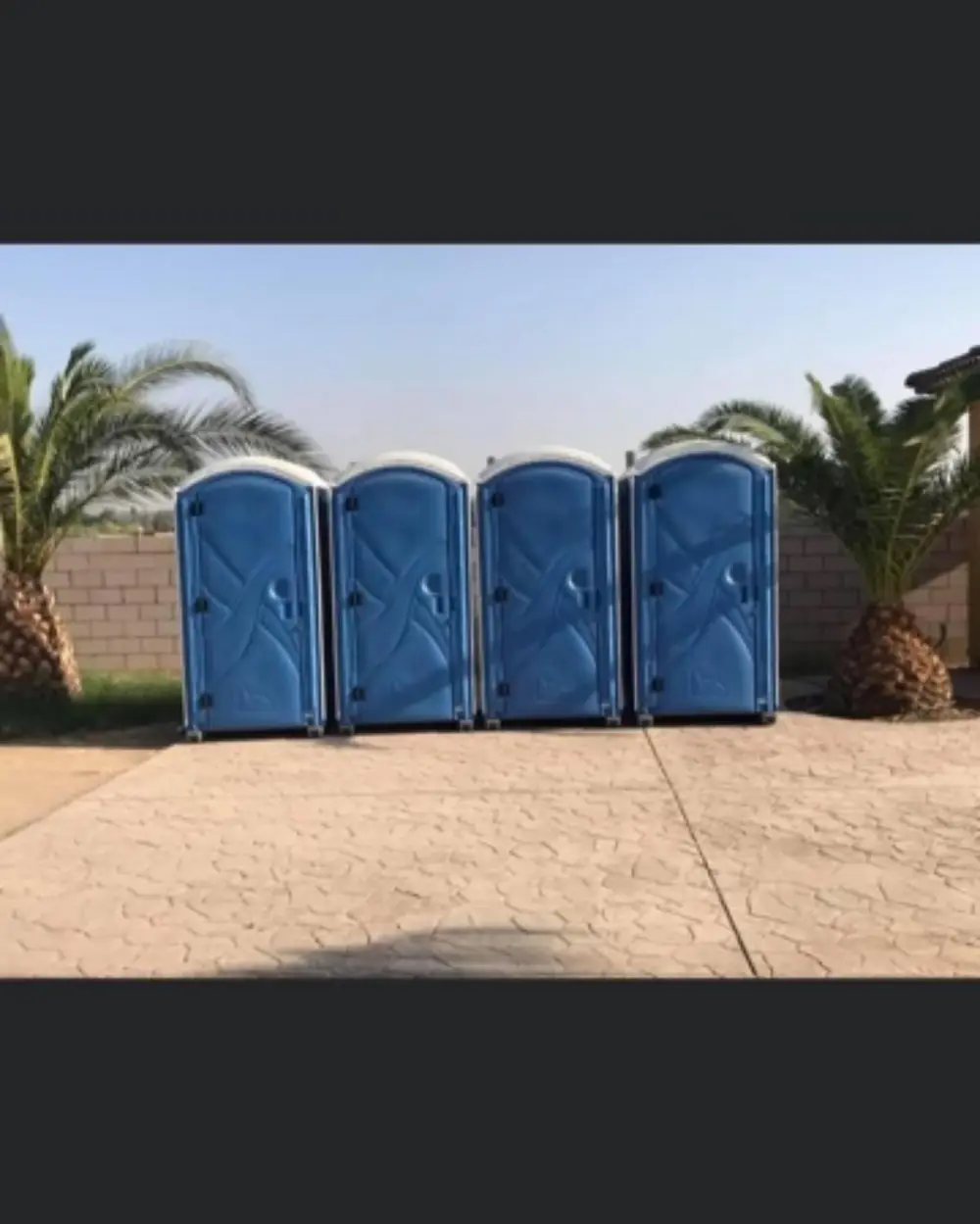 Four blue portable toilets lined up and ready to load
