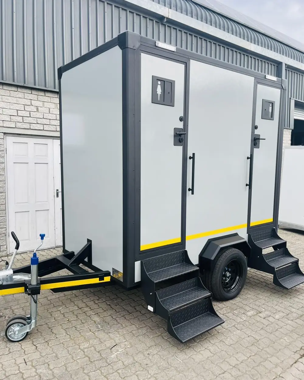Two-door restroom trailer with fold-down steps