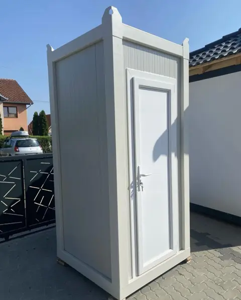White flushing restroom cabin in a home driveway